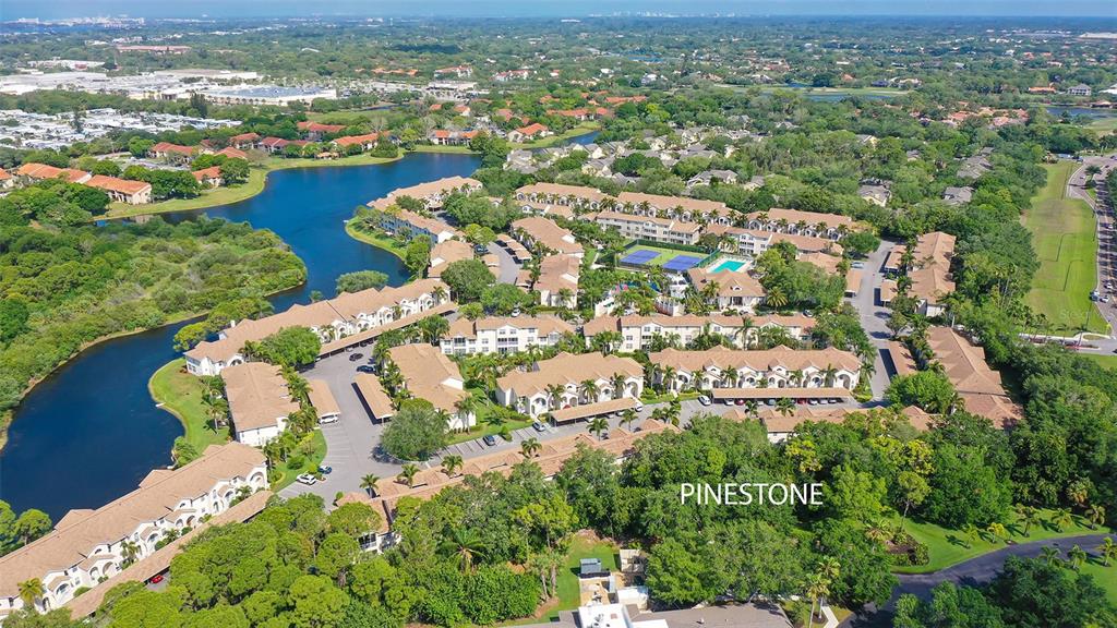 An aerial view shows a residential complex with multiple buildings, a lake, and tennis courts — 4205 CASTLEBRIDGE LANE UNIT 1112, SARASOTA, FL