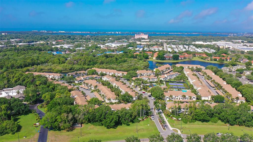 An aerial view shows a residential complex with multiple buildings, a pool, and surrounding greenery — 4205 CASTLEBRIDGE LANE UNIT 1112, SARASOTA, FL