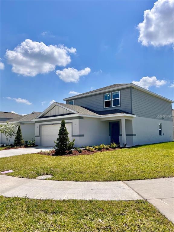 A two-story house with a white stucco lower level and gray siding on the upper level — 1297 REGAL KING DRIVE, KISSIMMEE, FL