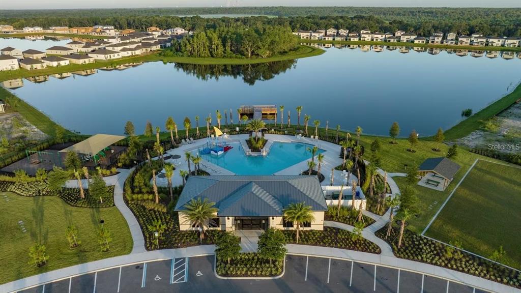 An aerial view shows a community clubhouse with a pool, playground, and lake — 1297 REGAL KING DRIVE, KISSIMMEE, FL