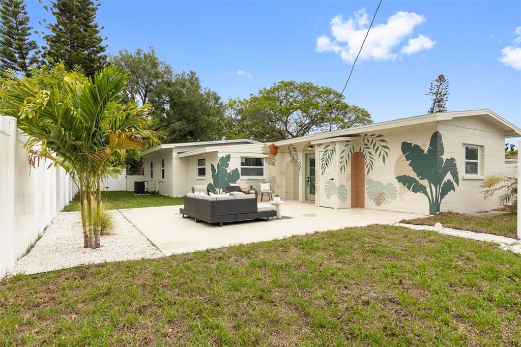A backyard features a patio with outdoor seating, a mural-painted house, and a palm tree — 7042 DARTMOUTH AVENUE N, ST PETERSBURG, FL