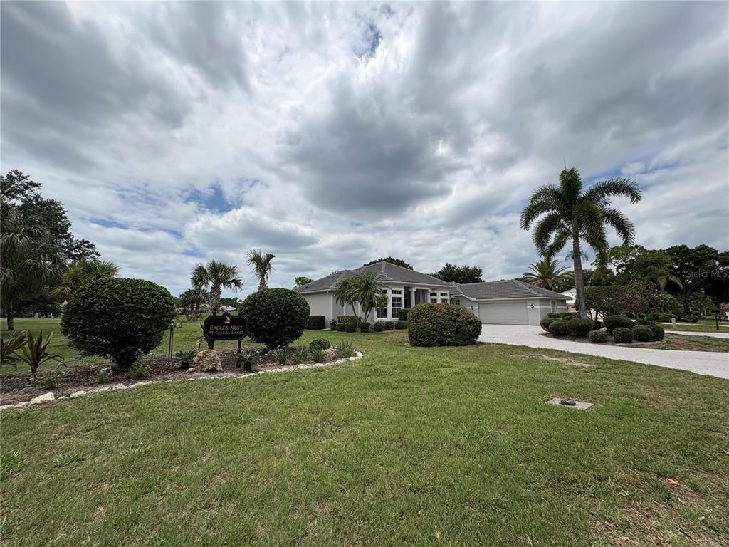 A single-story house with a paved driveway and a landscaped front yard under a cloudy sky — 2181 CALUSA LAKES BOULEVARD, NOKOMIS, FL