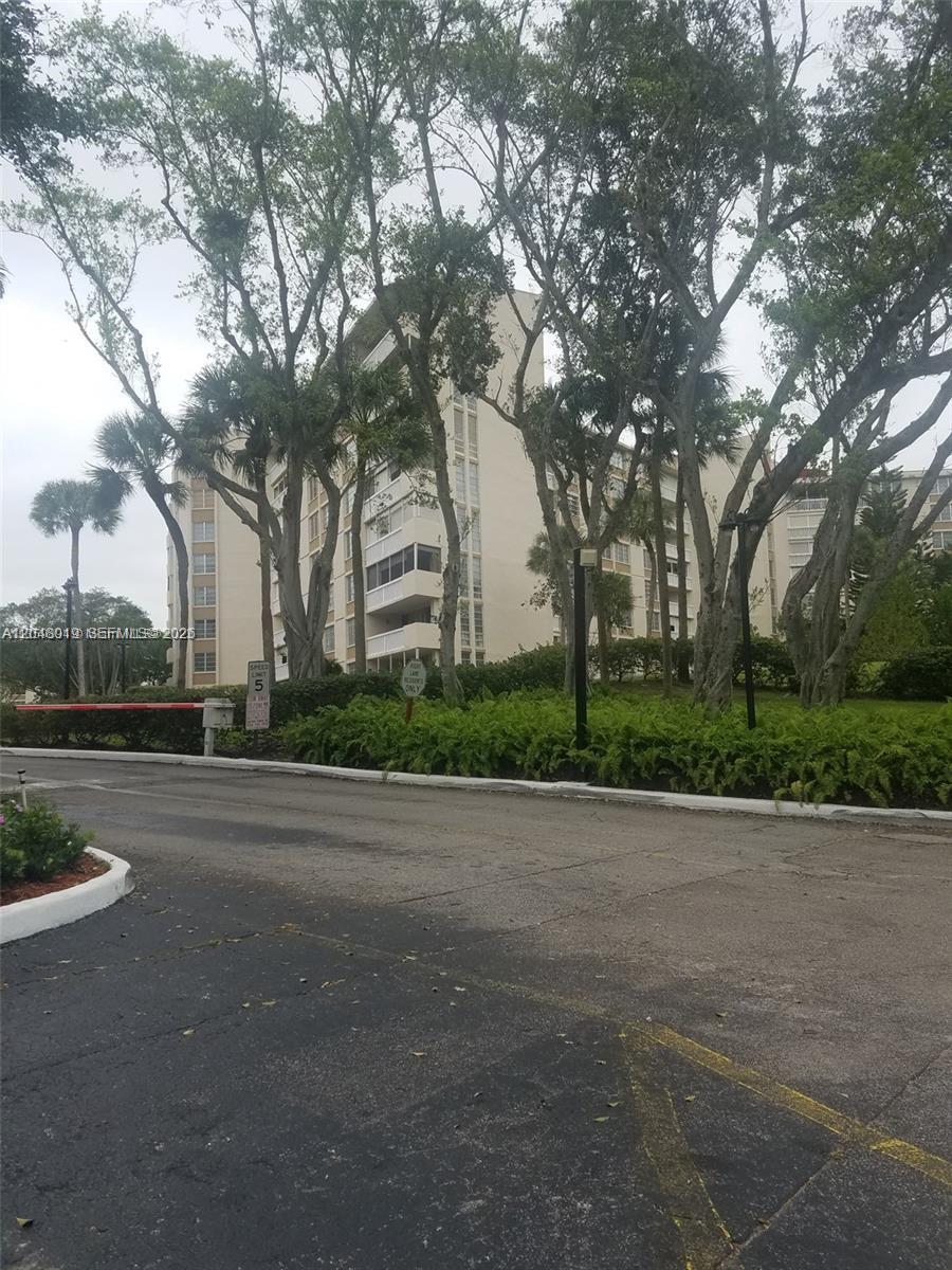 A multi-story apartment building stands behind a paved driveway and lush green landscaping — 6921 Environ Blvd # 4P, Lauderhill FL 33319, LAUDERHILL, FL