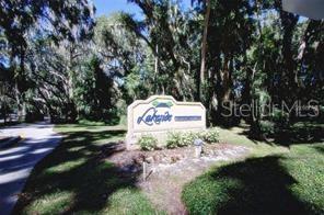 A stone sign for Lakeside Condominiums stands in a grassy area surrounded by mature trees — 120 HIBISCUS WOODS COURT UNIT 10B, DELTONA, FL