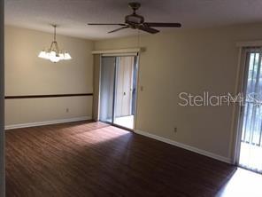 A living and dining area features wood-look flooring, a ceiling fan, and sliding glass doors — 120 HIBISCUS WOODS COURT UNIT 10B, DELTONA, FL