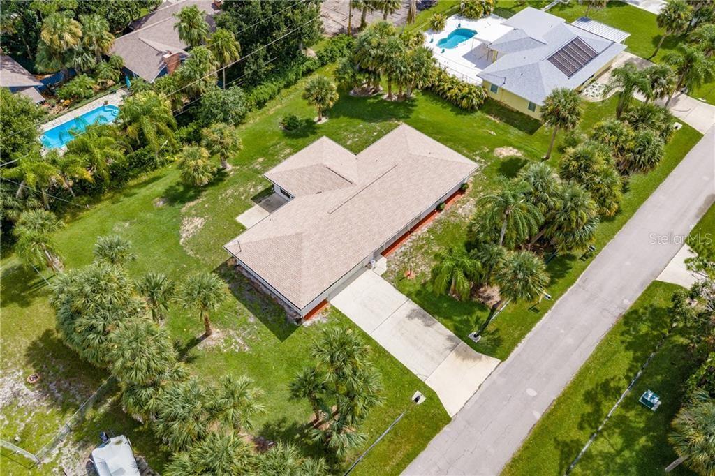 An aerial view shows a single-story house with a tan roof, driveway, and surrounding palm trees — 374 CITRUS AVENUE, SEBASTIAN, FL