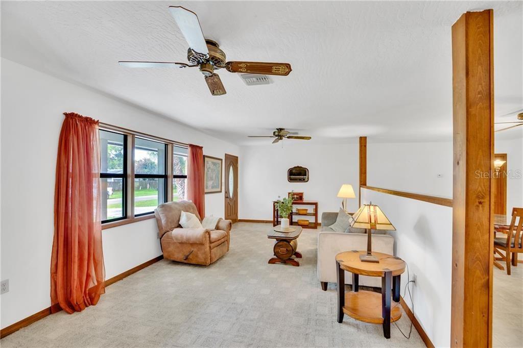 A living room features carpeted floors, two ceiling fans, and a partial wooden room divider — 374 CITRUS AVENUE, SEBASTIAN, FL