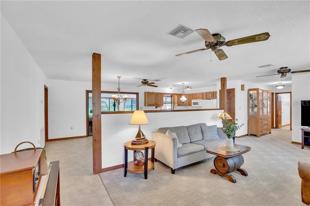 A living room with a gray sofa, wood-topped barrel table, and an open kitchen beyond — 374 CITRUS AVENUE, SEBASTIAN, FL