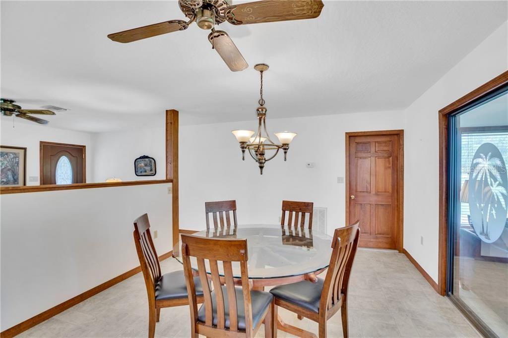 A dining area features a glass-topped table, wooden chairs, a ceiling fan, and a chandelier — 374 CITRUS AVENUE, SEBASTIAN, FL
