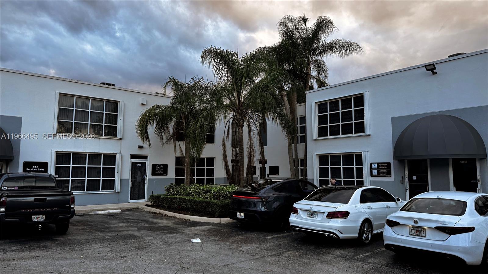 A two-story commercial building exterior features white walls, large windows, and palm trees — 13406 SW 128th St, Miami FL 33186, MIAMI, FL