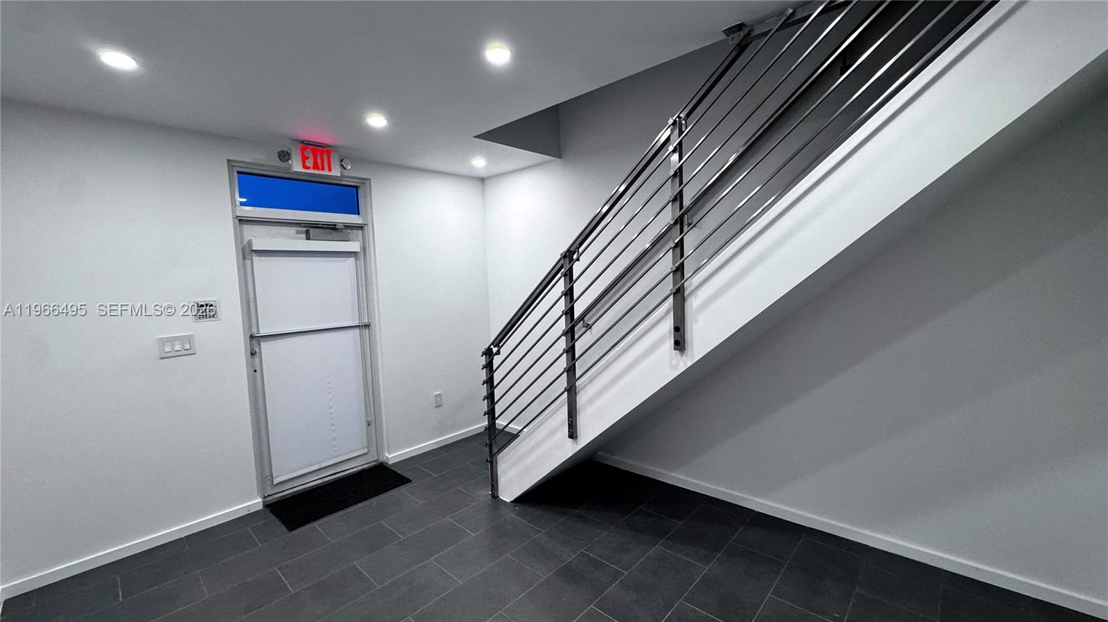 A modern entryway features a metal staircase, white walls, and dark gray floor tiles — 13406 SW 128th St, Miami FL 33186, MIAMI, FL