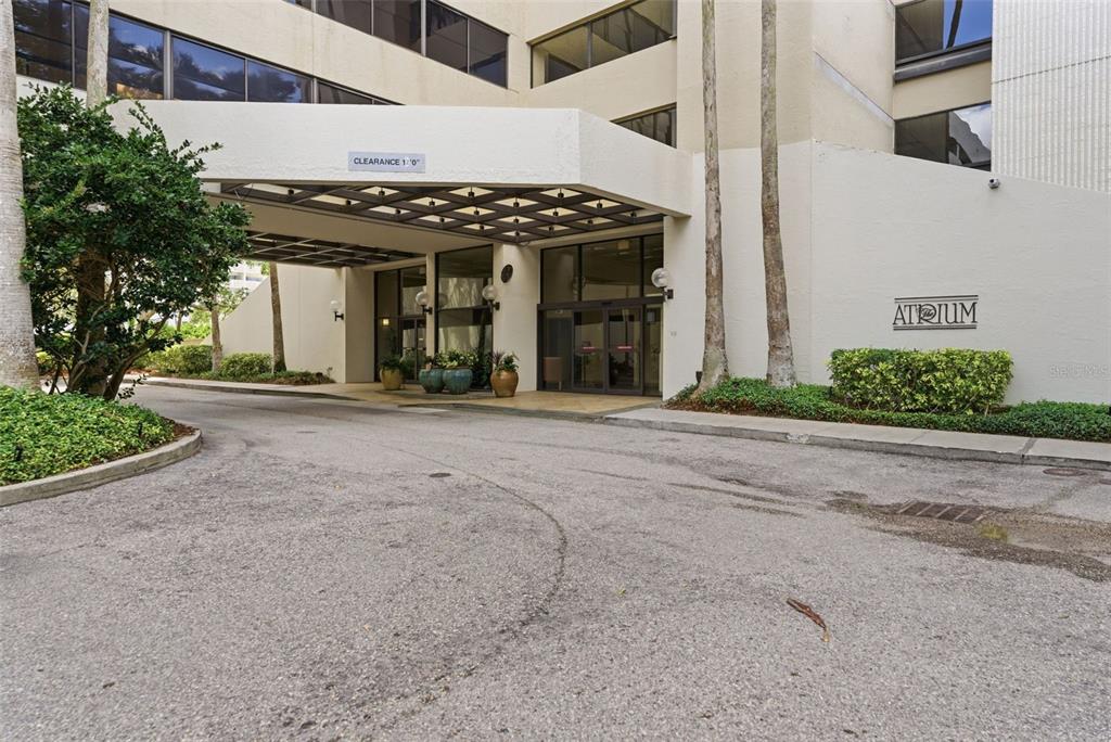 The exterior entrance of a multi-story building features a covered driveway and a glass doorway — 2413 BAYSHORE BOULEVARD UNIT 1004, TAMPA, FL