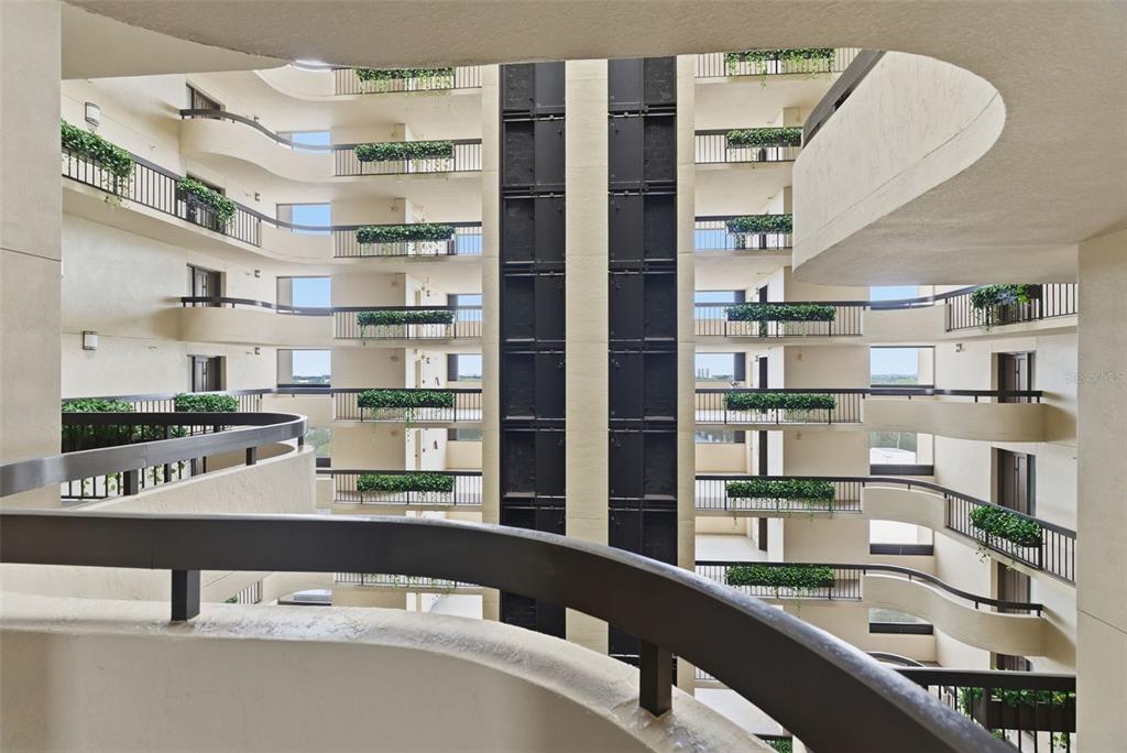 A view from a curved balcony looking across an open-air atrium of a multi-story building — 2413 BAYSHORE BOULEVARD UNIT 1004, TAMPA, FL