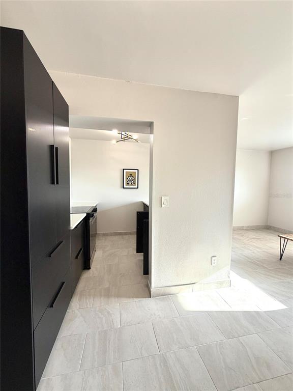 A kitchen with dark cabinets and light tile flooring opens into a living area — 2525 W BAY DRIVE UNIT C34, LARGO, FL