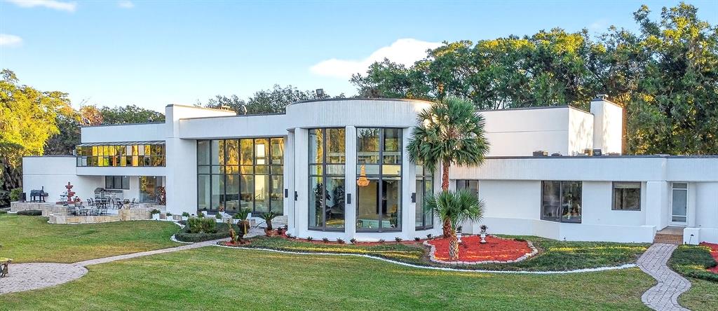 A large, modern white house with floor-to-ceiling windows and a curved central facade — 812 SWEETWATER CLUB BOULEVARD, LONGWOOD, FL