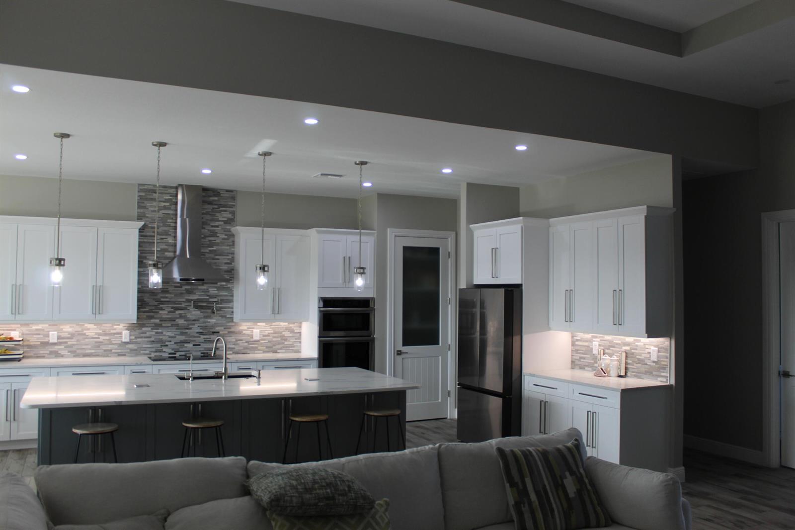 A modern kitchen features white cabinets, a dark gray island, stainless steel appliances, and tile backsplash — 3502 S Brocksmith Road, Fort Pierce FL 34945, FORT PIERCE, FL