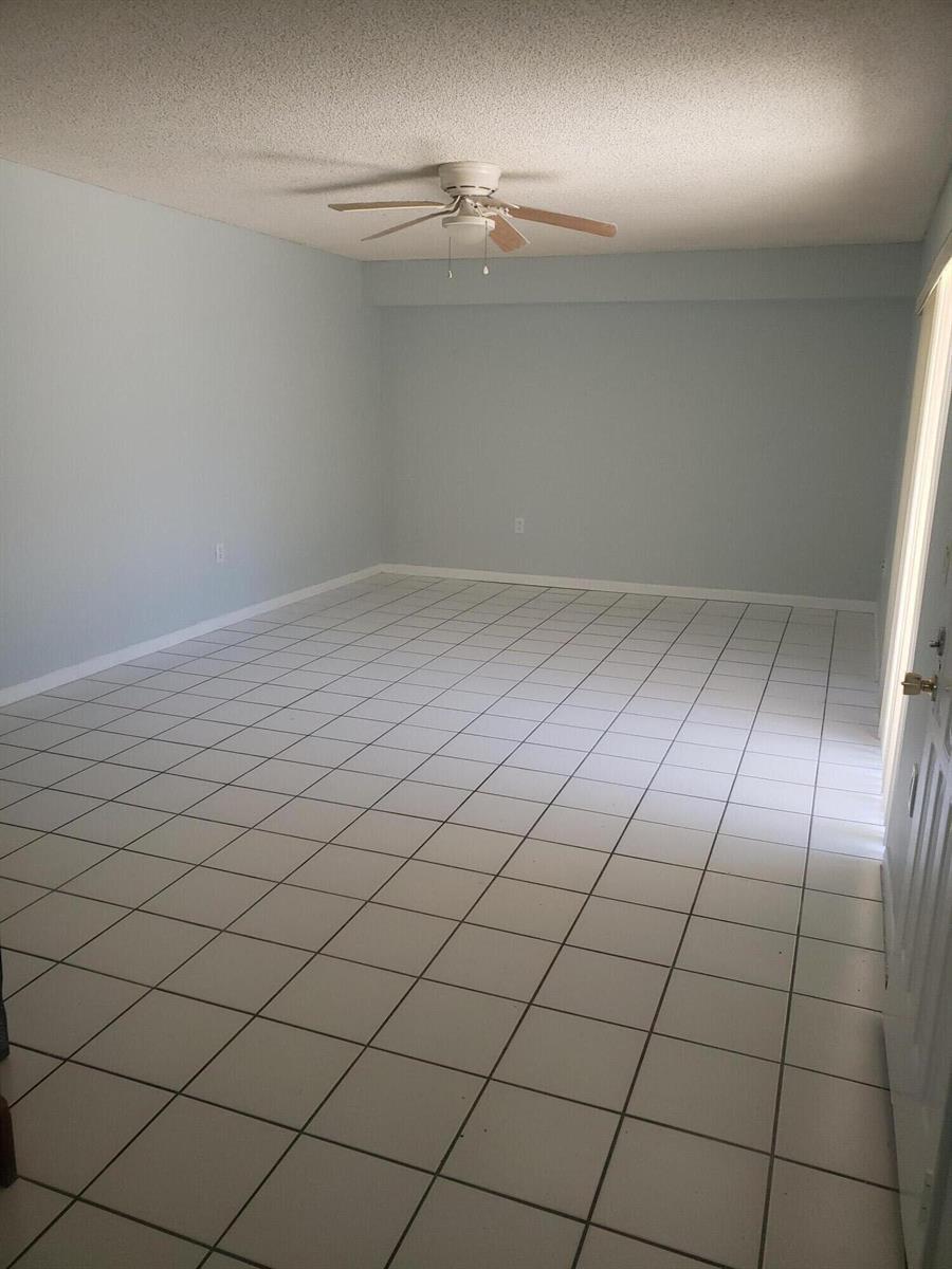 An empty room with light blue walls, white tiled flooring, and a ceiling fan — 3209 32nd Way, West Palm Beach FL 33407, WEST PALM BEACH, FL