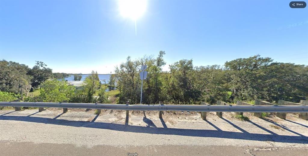 A view of a lake seen from behind a metal guardrail and roadside vegetation — N/A, POLK CITY, FL