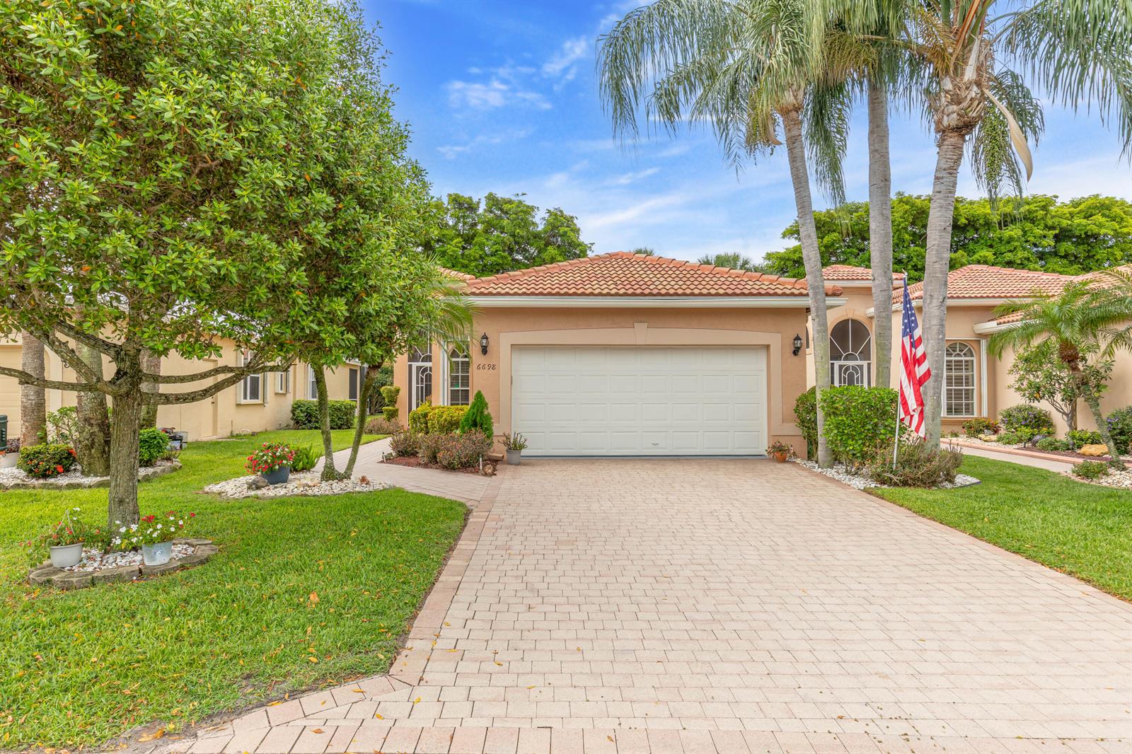 A single-story house with a beige stucco exterior, a tiled roof, and a paved driveway — 6698 Vía Roma, Delray Beach FL 33446, DELRAY BEACH, FL