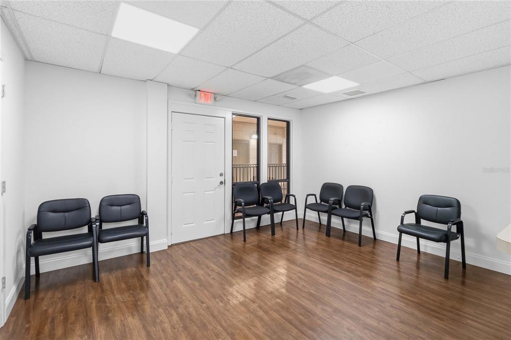 A waiting room with wood-look flooring, white walls, a drop ceiling, and several black chairs — 201 HILDA STREET UNIT 22, KISSIMMEE, FL