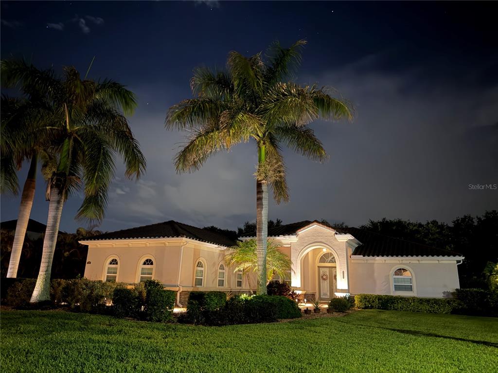 A single-story house with a tiled roof and palm trees at night — 380 165TH COURT NE, BRADENTON, FL