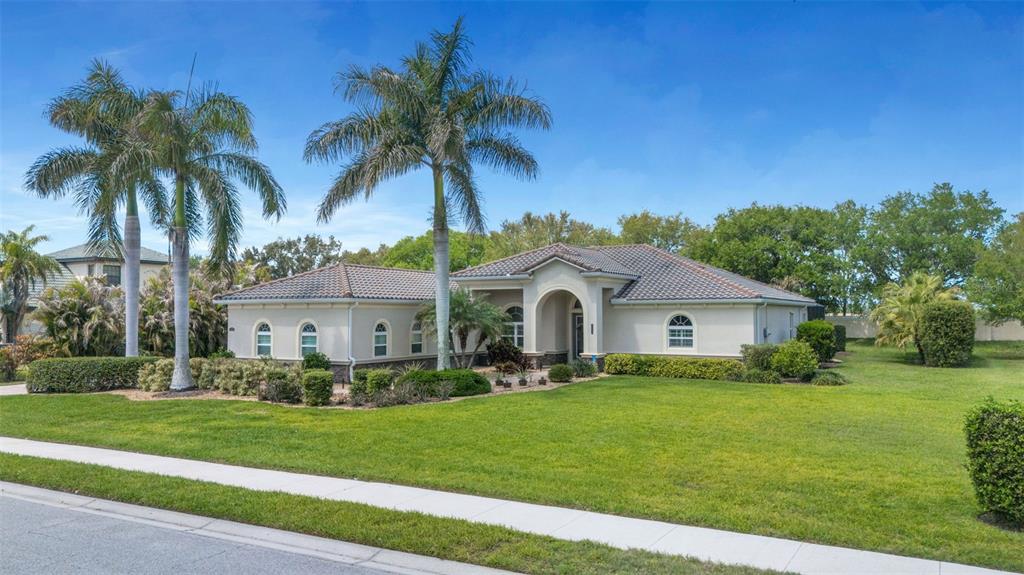 A single-story house with a tiled roof and two tall palm trees in the front yard — 380 165TH COURT NE, BRADENTON, FL