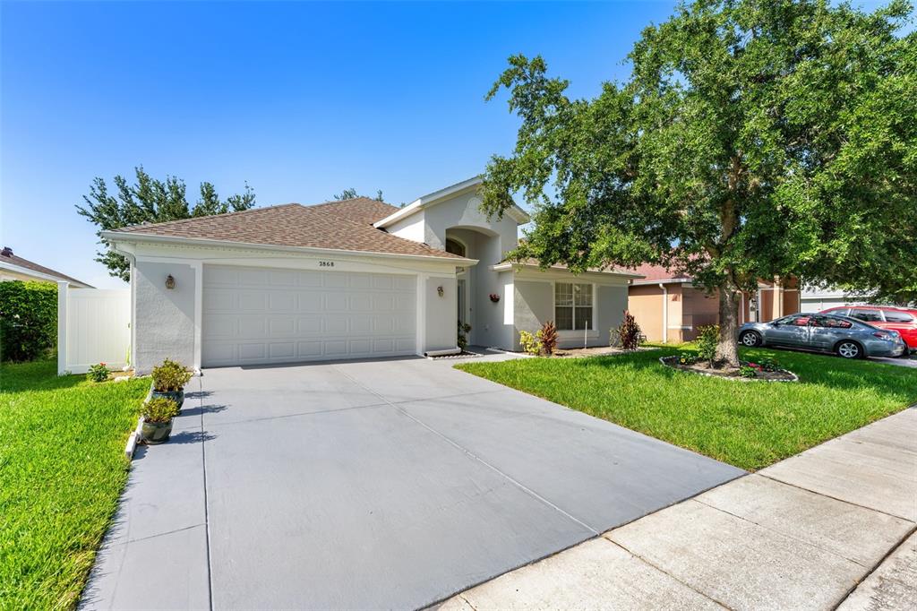 A single-story house with a two-car garage, a concrete driveway, and a large front tree — 2868 OCONNELL DRIVE, KISSIMMEE, FL