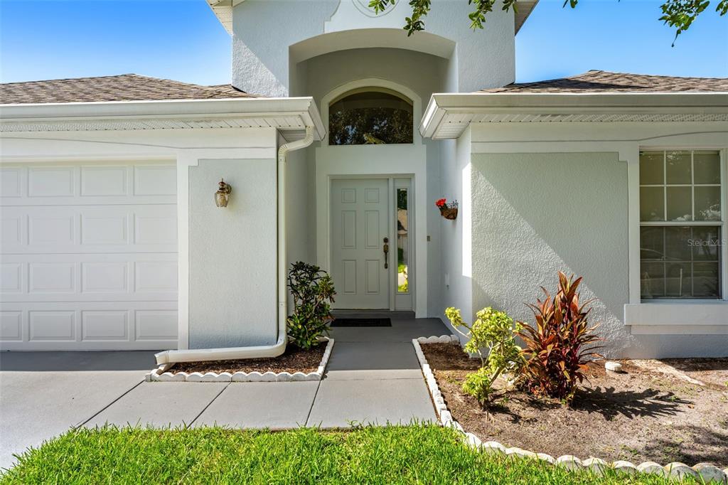 The exterior of a light-colored house features a white garage door and a front entrance — 2868 OCONNELL DRIVE, KISSIMMEE, FL