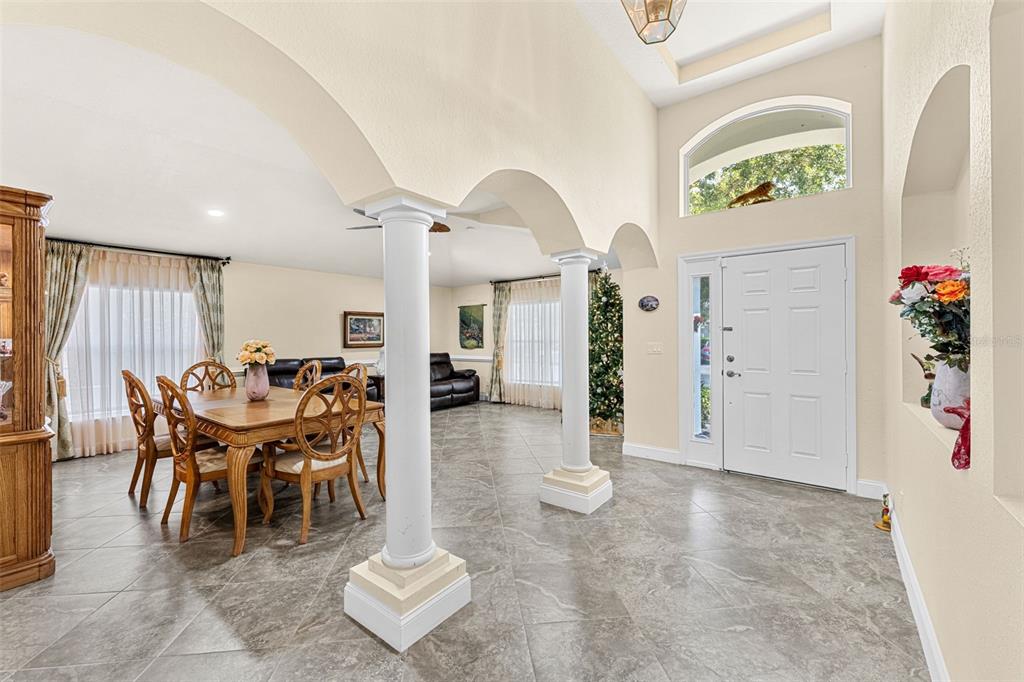 A dining area and entryway with tiled floors, white columns, and arched architectural details — 2868 OCONNELL DRIVE, KISSIMMEE, FL