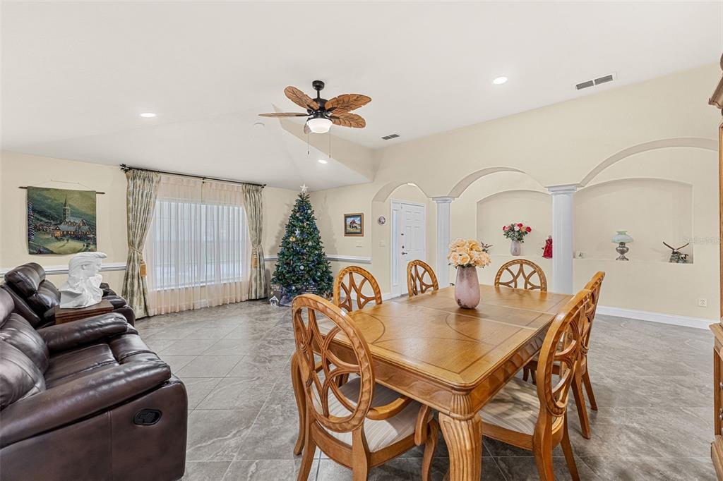 A dining area with a wooden table and chairs adjacent to a living room space — 2868 OCONNELL DRIVE, KISSIMMEE, FL