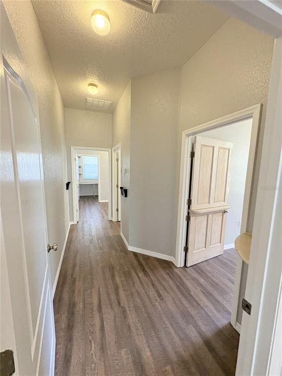 A hallway with wood-look flooring leads to multiple rooms featuring white doors and light gray walls — 1701 NE 42ND AVENUE UNIT 403, OCALA, FL