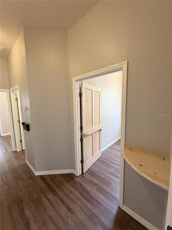 A hallway with wood-look flooring leads to a room with a light wood Dutch door — 1701 NE 42ND AVENUE UNIT 403, OCALA, FL