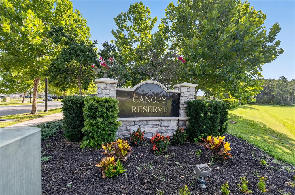A stone monument sign for Canopy Reserve stands in a landscaped garden with trees — 3438 BARINA STREET, ST CLOUD, FL