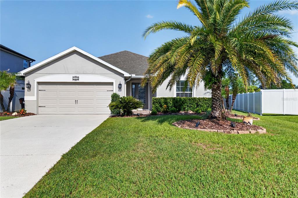 A single-story house with a two-car garage, a palm tree, and a white fence — 3438 BARINA STREET, ST CLOUD, FL
