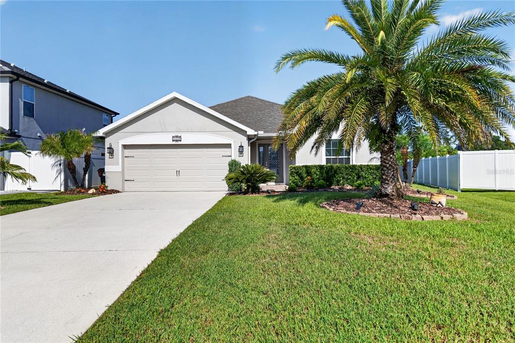 A single-story house with a two-car garage, a palm tree, and a white fence — 3438 BARINA STREET, ST CLOUD, FL