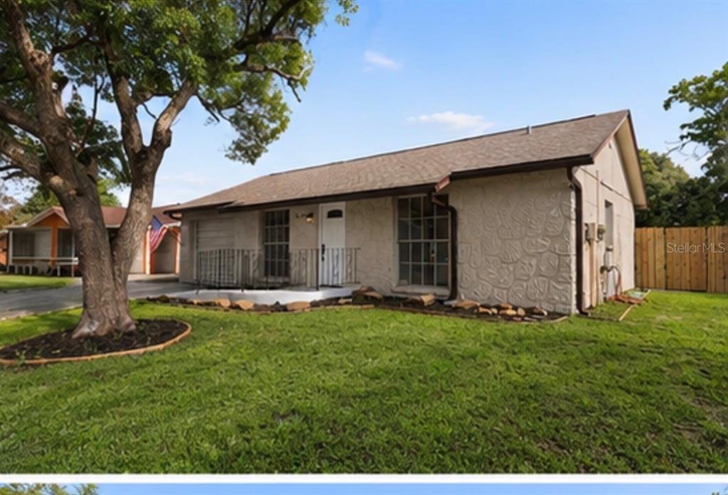 A single-story house with a textured stone facade, a front porch, and a large tree — 7645 ARLIGHT DRIVE, NEW PORT RICHEY, FL