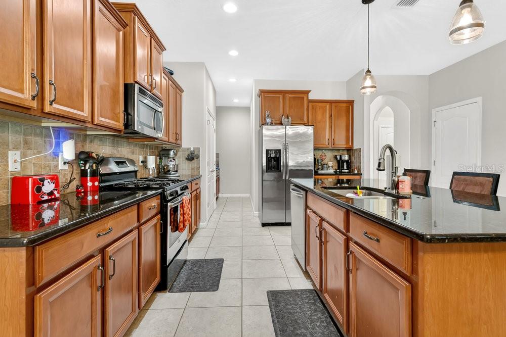 A kitchen with wood cabinets, stainless steel appliances, and a dark granite island countertop — 632 MEADOW SAGE DRIVE, DELAND, FL