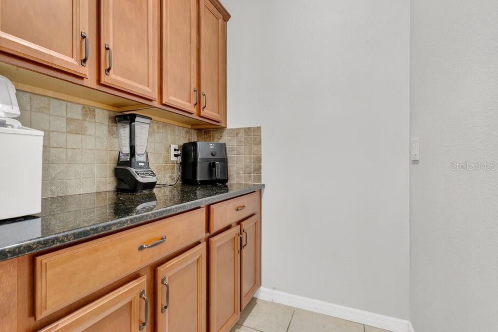 A kitchen counter features wooden cabinets, a tiled backsplash, a blender, and an air fryer — 632 MEADOW SAGE DRIVE, DELAND, FL