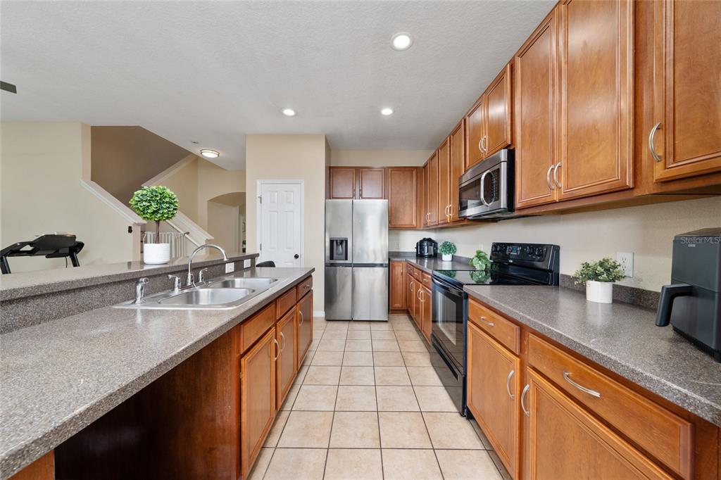 A kitchen with wood cabinets, stainless steel appliances, and a breakfast bar with a sink — 3008 SEAVIEW CASTLE DRIVE, KISSIMMEE, FL
