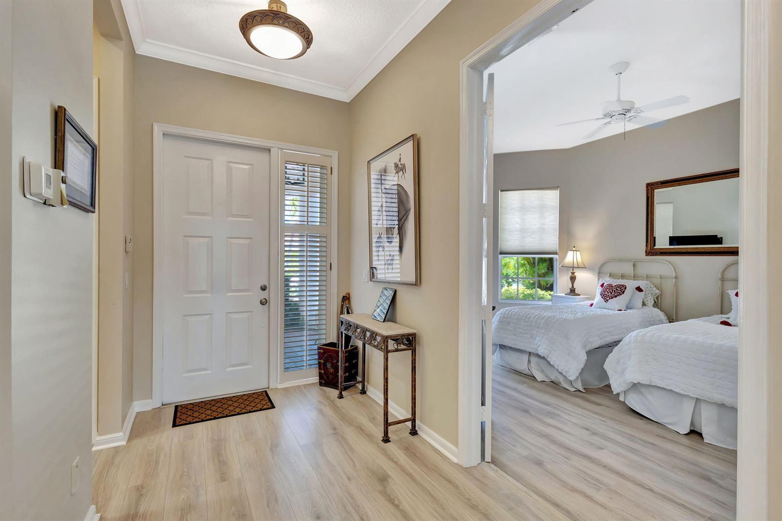 An entryway with light wood floors leads into a bedroom featuring two twin beds — 2941 Twin Oaks Way, Wellington FL 33414, WELLINGTON, FL