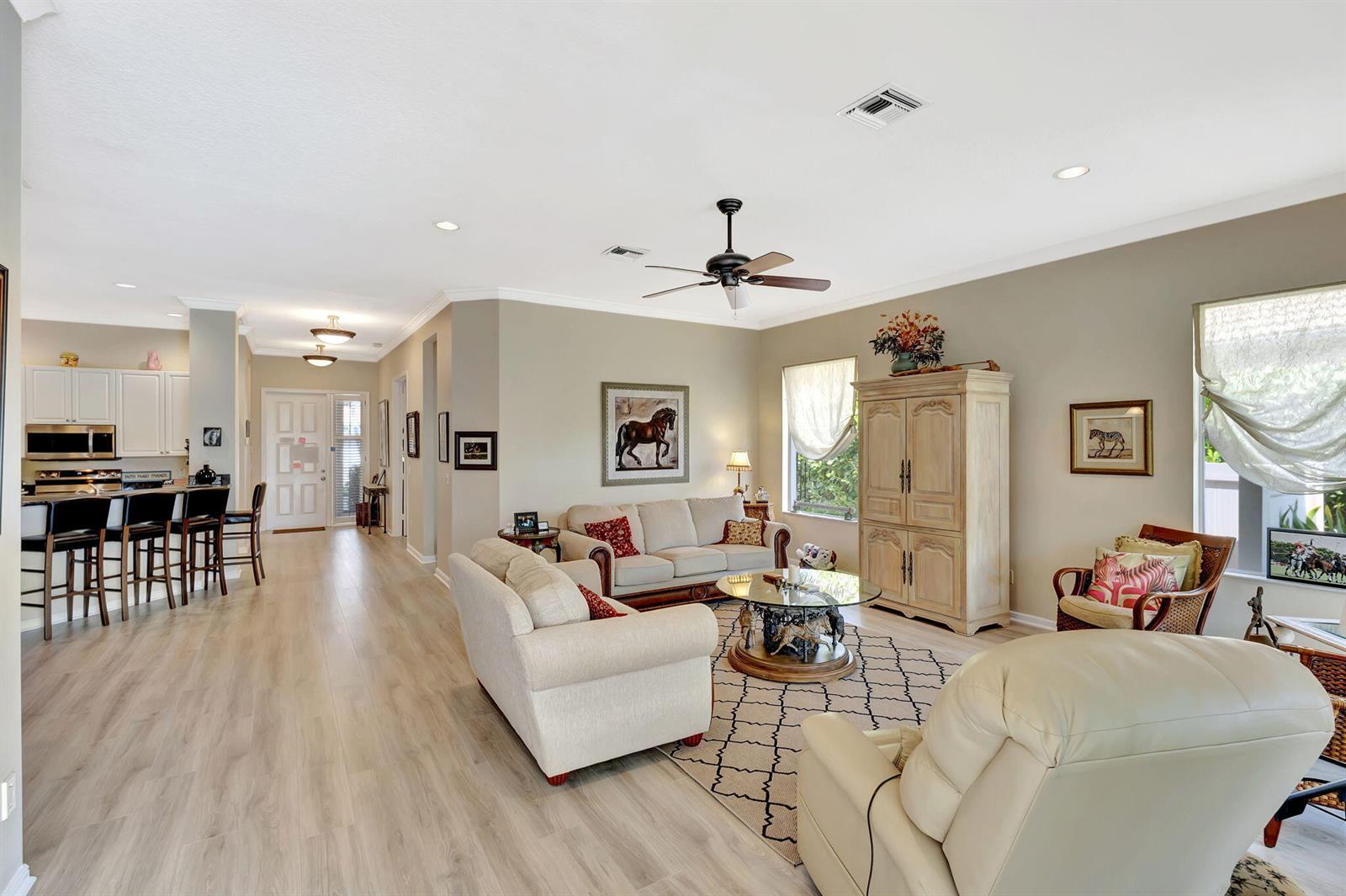 A living room with light wood floors, a ceiling fan, and an open kitchen area — 2941 Twin Oaks Way, Wellington FL 33414, WELLINGTON, FL