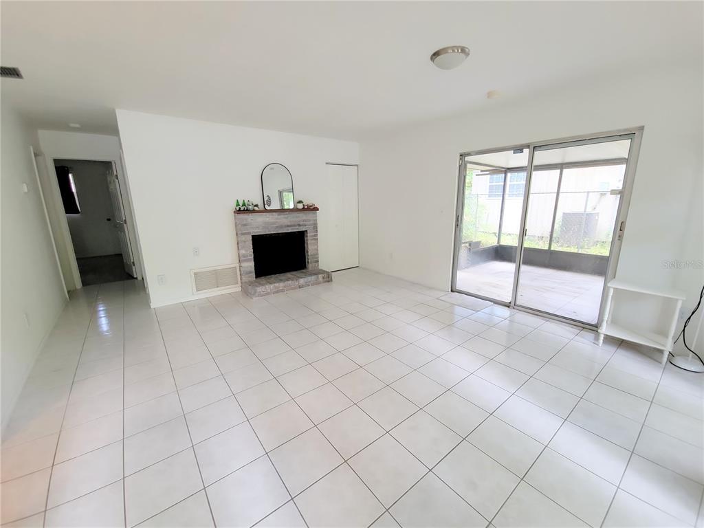 A living room features white tile floors, a brick fireplace, and sliding glass doors — 3301 NW 19TH STREET, GAINESVILLE, FL
