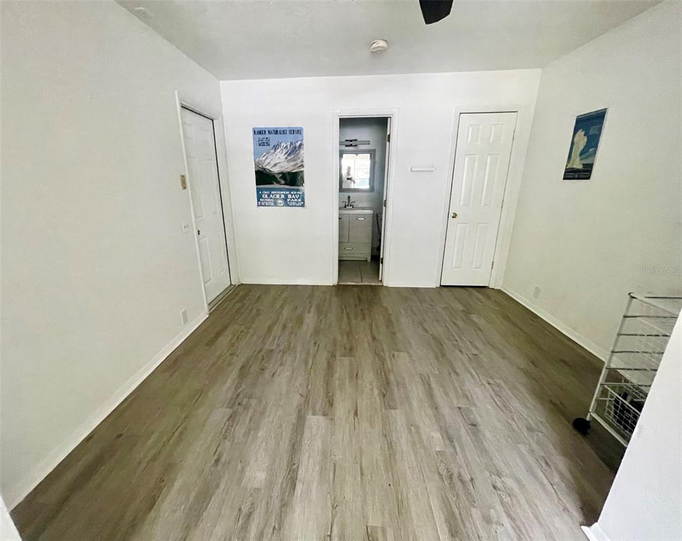 An empty room features light-colored wood-look flooring, two white doors, and a central bathroom doorway — 3301 NW 19TH STREET, GAINESVILLE, FL