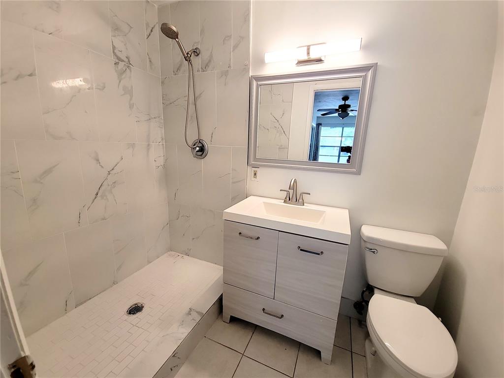 A bathroom features a walk-in shower with marble-look tile, a vanity, and a toilet — 3301 NW 19TH STREET, GAINESVILLE, FL