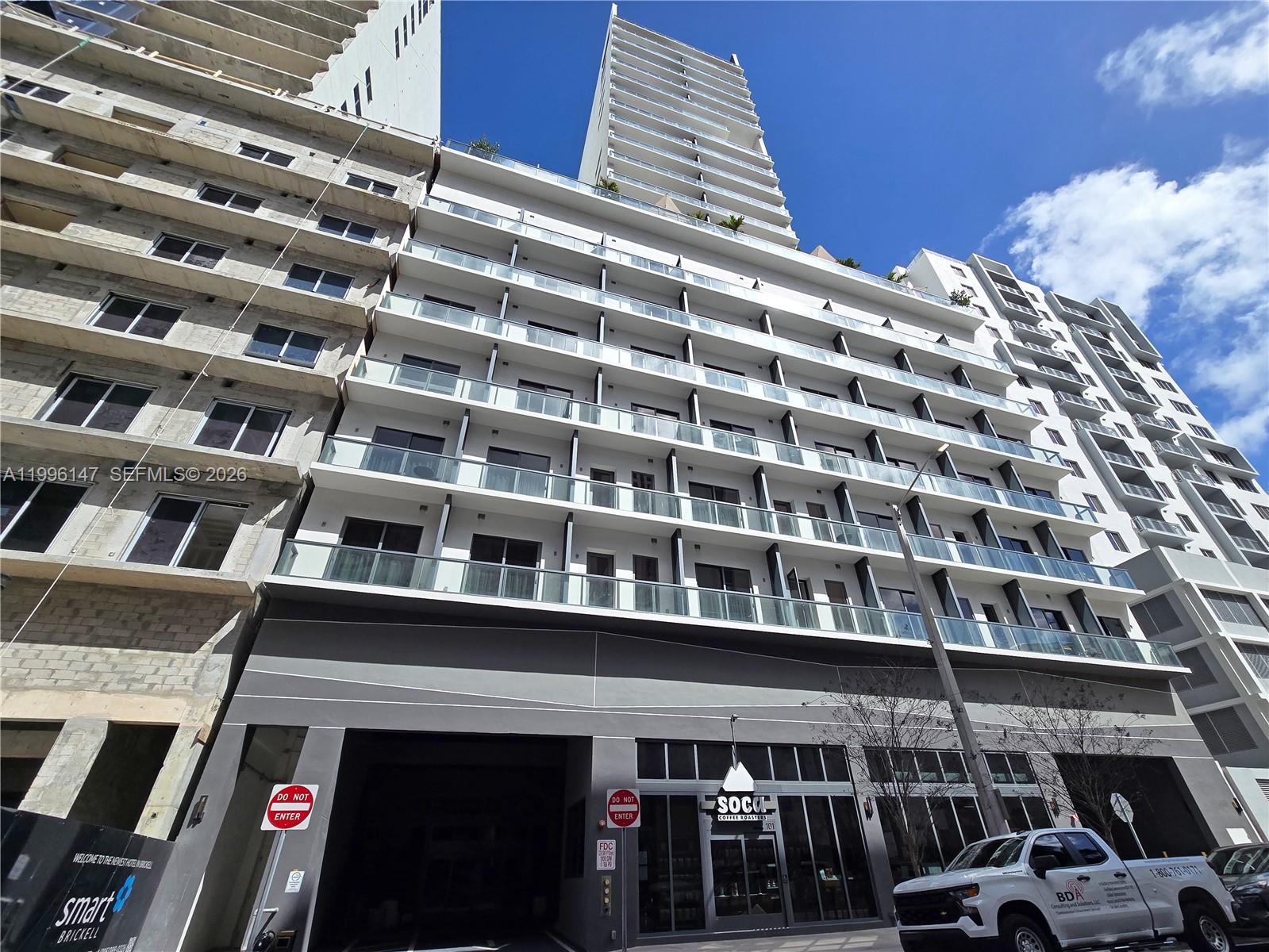 A modern high-rise building features glass balconies and a ground-floor coffee shop entrance — 239 SW 9th St # 1403, Miami FL 33130, MIAMI, FL