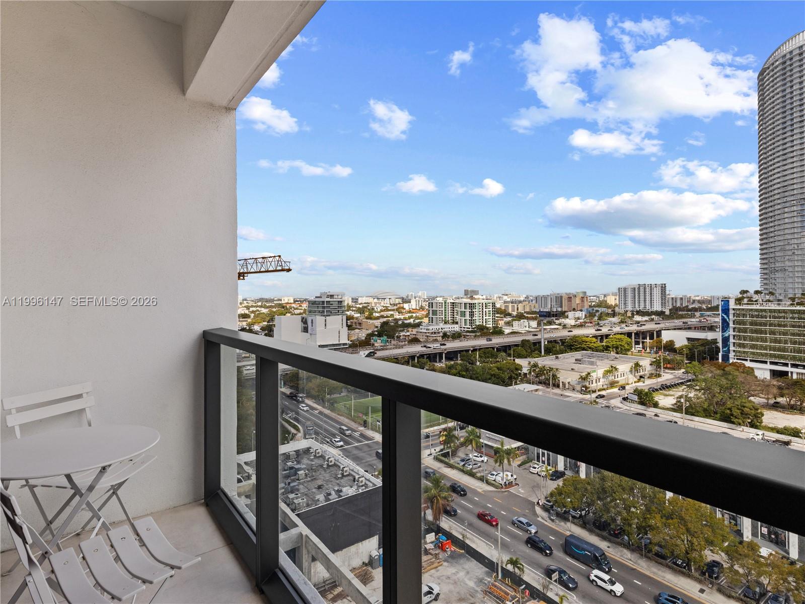 A balcony with a white bistro set overlooks a city street and highway — 239 SW 9th St # 1403, Miami FL 33130, MIAMI, FL