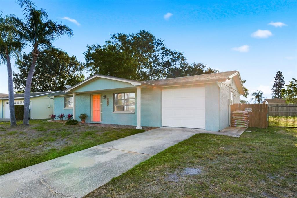 A light blue single-story house with a white garage door and a bright orange front door — 1958 ESSEX DRIVE, HOLIDAY, FL