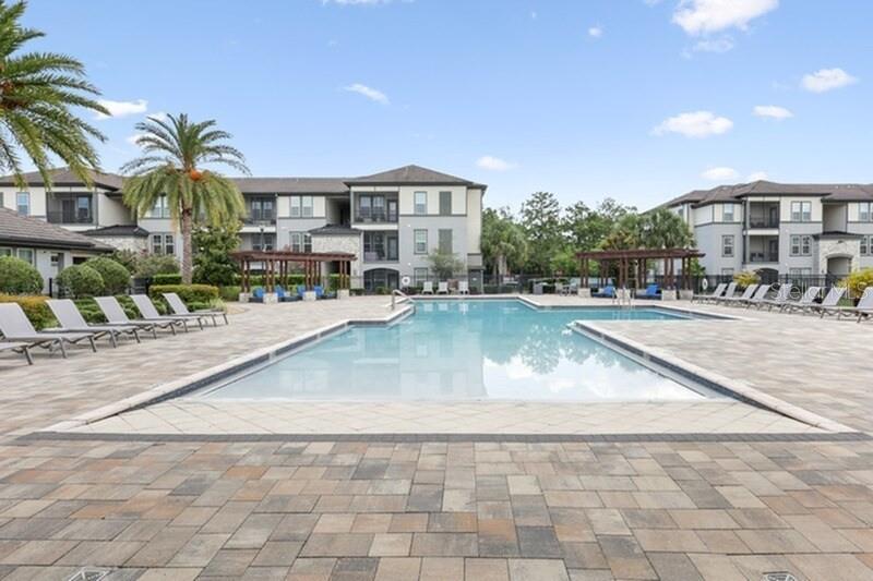 An outdoor swimming pool surrounded by a paved deck and apartment buildings — 11128 GRANDE PINES CIRCLE UNIT Horizon, ORLANDO, FL
