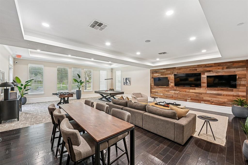 A spacious recreation room features a dining table, sectional sofa, pool table, and wood-paneled wall — 11128 GRANDE PINES CIRCLE UNIT Horizon, ORLANDO, FL