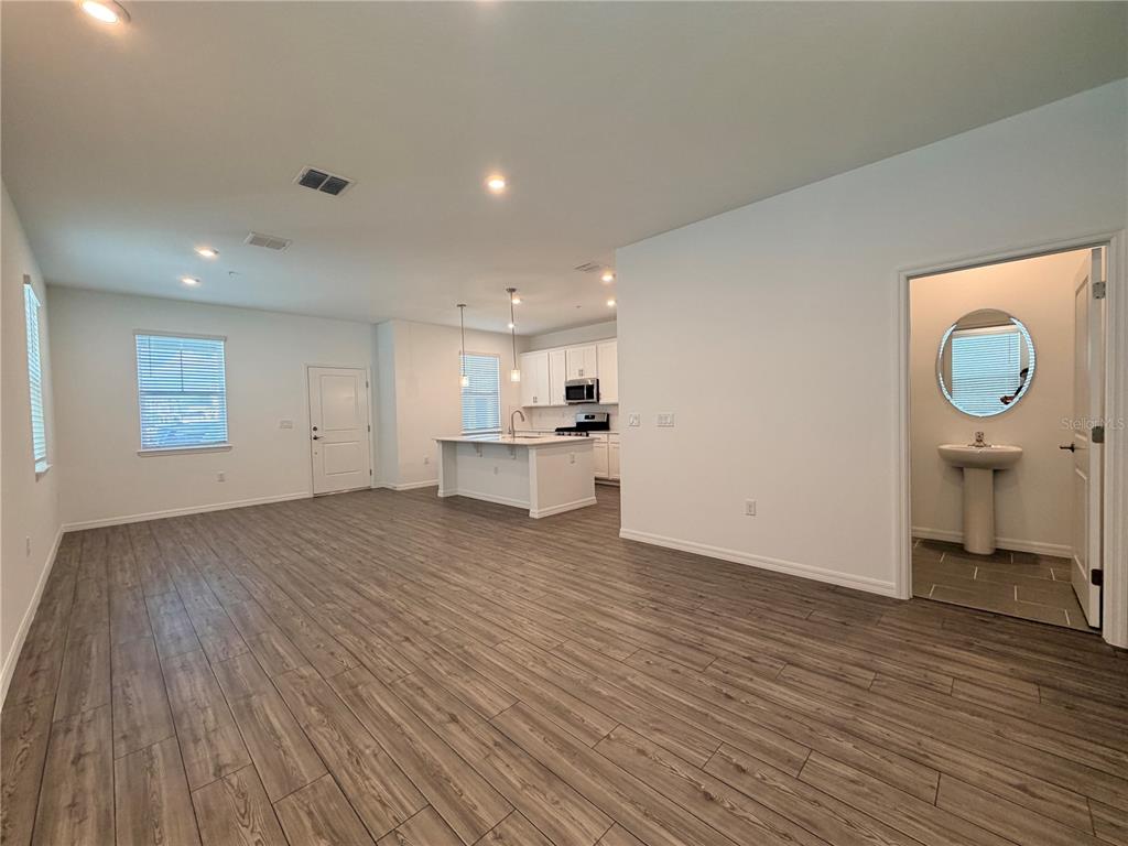An open-concept living area features wood-look flooring, a kitchen island, and an adjacent half bathroom — 449 BELMOND DRIVE, DEBARY, FL